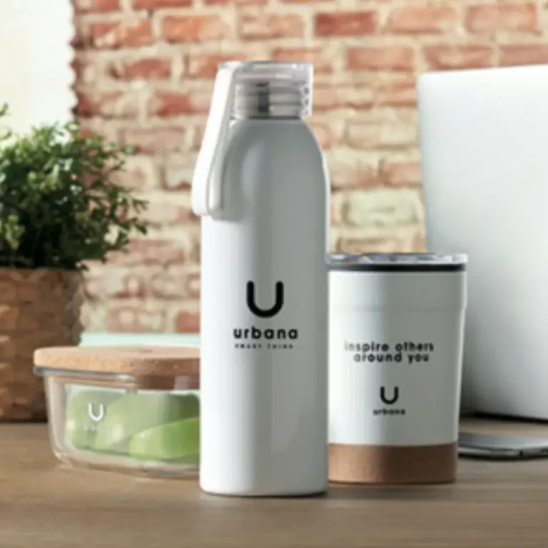 Una botella, un vaso, y un recipiente con el logo "Urbana" sobre una mesa de madera.
