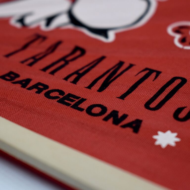 Primer plano de una tela roja con el texto "TARANTO BARCELONA" en negro.