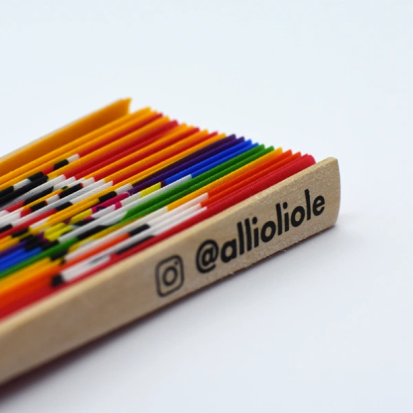 Primer plano de un abanico plegado con varillas de colores y el logo "@allioliole".