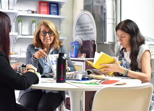 Reunión de trabajo con regalos publicitarios personalizados, como botellas y materiales promocionales para empresas y eventos.